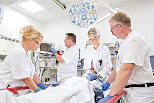Four caregivers tending to a patient in intensive care.
